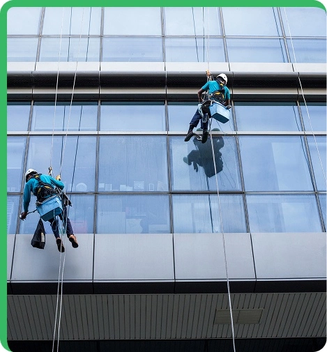 worker hanging an performing cleaning on windows of a tall building